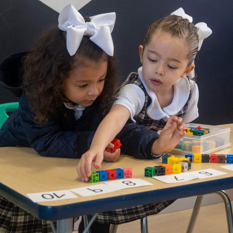 Niña sonriente en uniforme escolar trabajando en una actividad en el aula de Kinder Grove