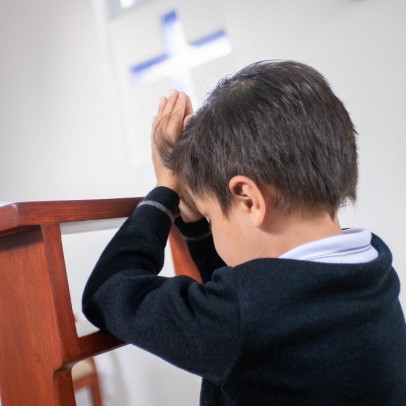 Alumno de Kínder Grove rezando en capilla
